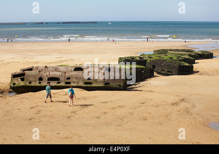 Besucher erkunden die Reste der Mulberry Hafen am Strand von Arromanches Normandie Frankreich im Juli Stockfoto