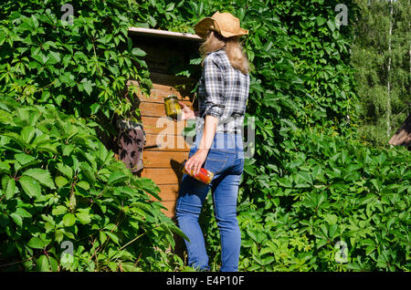 Bauer-Frau mit Hut zu Fuß zum ländlichen Keller Haus Kellertür mit Konserven bewahren Essen Gläser Töpfe. Stockfoto