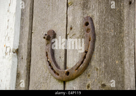 Eisen alte rostige Hufeisen-Symbol des Glücks auf hölzernen Hintergrund Stockfoto