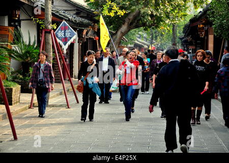 ANTIKE Stadt LANGZHONG (SICHUAN), CHINA: Reiseführer mit ihren gelben Flagge führt eine große Gruppe von chinesischen Touristen Stockfoto