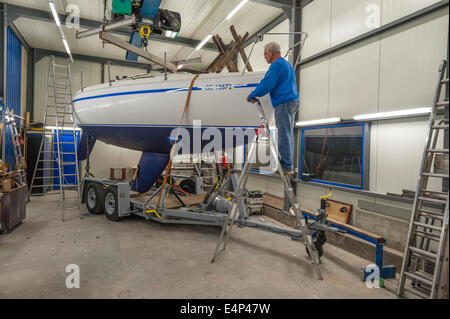 Ein Mann auf einem Segelboot in einer Werkstatt arbeitet Stockfoto