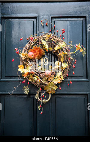 Herbstliche Dekoration Kranz mit herbstlichen Blättern und Früchten auf eine hölzerne Tür, Eingang eines Hauses Stockfoto