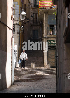 Aus der Dunkelheit ins Licht. Ein Mann steigt eine dunkle Schatten Straße Treppe in hellem Sonnenlicht im Bereich Ghetto Gironas. Stockfoto