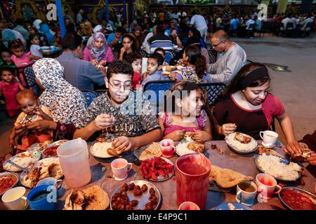 Kairo, Ägypten. 15. Juli 2014. Ägypter genießen Sie ihre Mahlzeiten bei einem Charity-Bankett in Kairo, Ägypten, 15. Juli 2014. Nächstenliebe Bankette oder ma'idat al-Rahman, eine langjährige Tradition der Ramadan in Ägypten, vertreten durch die wohlhabende Gönner ihre weniger wohlhabenden Glaubensgenossen zu den Mahlzeiten bieten, das Fasten zu brechen. © Cui Xinyu/Xinhua/Alamy Live-Nachrichten Stockfoto