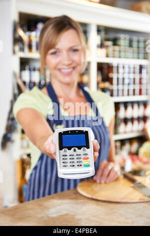Verkäufer, Verkäuferin im Lebensmittelgeschäft Kreditkarte Maschine an Kunden übergeben Stockfoto