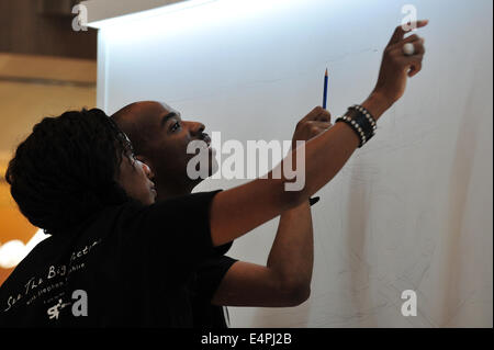 Singapur. 16. Juli 2014. Großbritanniens autistische Künstler Stephen Wiltshire (R) zieht, während seine Schwester Annette am ersten Tag seines Erscheinens in Singapurs Paragon Shopping Centre, 16. Juli 2014 unterstützt. Singapore Press Holdings (SPH) lud Stephen Wiltshire, ein Panorama von Singapur Mittwoch ziehen. Bildnachweis: Dann Chih Wey/Xinhua/Alamy Live News Stockfoto