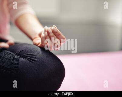 Geringer Teil der Frau sitzt im Schneidersitz auf Mat Meditation im Yoga-Haltung. Bild der Frau praktizieren Yoga mit Fokus o beschnitten Stockfoto