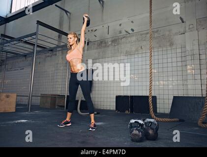 Junge Fitness Frau heben eine schweres Gewicht Wasserkocher Glocke im Fitnessstudio. Kaukasische weiblichen Athleten trainieren Sie im Fitnesscenter. Fit junge Dame zu tun Stockfoto