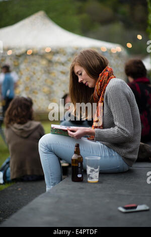 Eine junge Frau liest das Programm der Veranstaltungen der Machynlleth Comedy Festivals 2014 Stockfoto