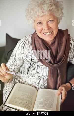 Fröhliche Reife Dame im Hause genießen ein gutes Buch Stockfoto