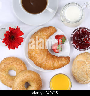 Gedeckter Tisch mit Frühstück, Brötchen, Marmelade, Kaffee und Orangensaft von oben Stockfoto