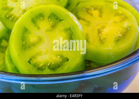 Geschnittene grüne Tomaten in eine blaue Glasschale. Stockfoto