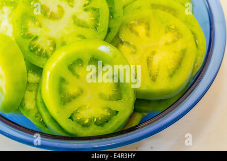 Geschnittene grüne Tomaten in eine blaue Glasschale. Stockfoto