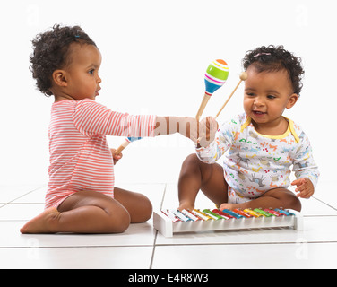 Zwei junge und ein Mädchen (18 Monate) spielt mit Xylophone und maracas Stockfoto