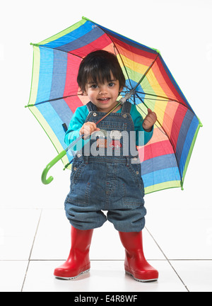 Kleiner Junge (16 Monate) tragen Gummistiefel und Holding-Dach Stockfoto