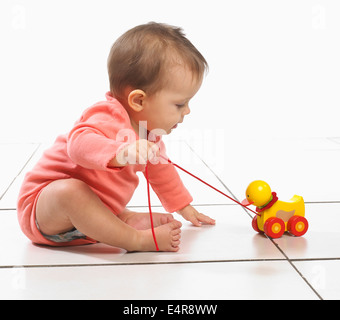 Baby Girl (8 Monate) ziehen entlang Spielzeug Ente auf Rädern Stockfoto