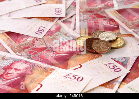 Hintergrund der britischen fünfzig Pfund Banknoten und einem Stapel von Münzen Stockfoto