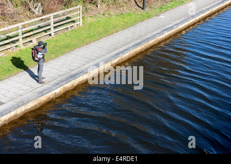 junger Mann fotografiert am Ufer des Flusses Stockfoto