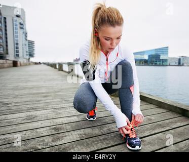 Fit und sportlich junge Frau vor einem Lauf ihre Schnürsenkel zu binden. Weibliche Läufer binden ihre Schnürsenkel während des Trainings im Freien. Stockfoto