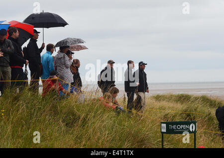 Royal Liverpool Golfclub, Hoylake, UK. 16. Juli 2014. Der offene letzte Praxis-Tag. Zuschauer, die bei starken Regenfällen in der Praxis unter Sonnenschirmen bergende Runden. Bildnachweis: Rsdphotography/Alamy Live-Nachrichten Stockfoto