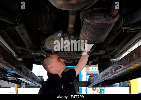 männliche Mitarbeiter ein altes Auto Auspuff System entfernt und ersetzt ihn durch einen neuen Stockfoto