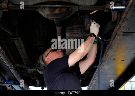 männliche Mitarbeiter ein altes Auto Auspuff System entfernt und ersetzt ihn durch einen neuen Stockfoto