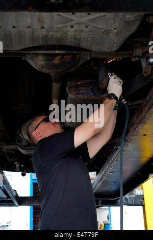 männliche Mitarbeiter ein altes Auto Auspuff System entfernt und ersetzt ihn durch einen neuen Stockfoto