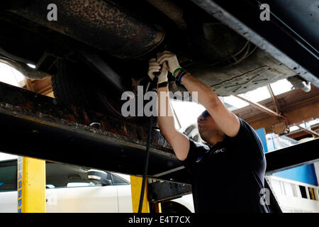 männliche Mitarbeiter ein altes Auto Auspuff System entfernt und ersetzt ihn durch einen neuen Stockfoto