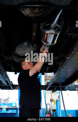 männliche Mitarbeiter ein altes Auto Auspuff System entfernt und ersetzt ihn durch einen neuen Stockfoto