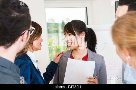 Gruppe von jungen Geschäftsleuten und Geschäftsfrau in Diskussion im Büro, junge Geschäftsfrau wird gratuliert, Deutschland Stockfoto