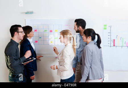 Gruppe von jungen Geschäftsleuten und Geschäftsfrau im Gespräch im Büro mit Whiteboard, Deutschland Stockfoto