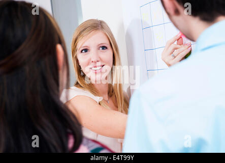 Nahaufnahme von drei jungen Geschäftsleuten treffen, stehen und blickte am Whiteboard im Büro, Deutschland Stockfoto