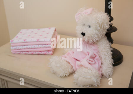 Stapel von Babydecke auf Kommode neben Teddybär und Lampe im Kinderzimmer Stockfoto