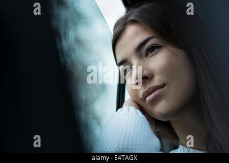 Porträt der jungen Frau im Auto sitzen und der Blick aus dem Fenster und Tagträumen an bewölkten Tag, Deutschland Stockfoto