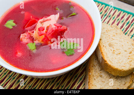 Ein Teller mit roten russische Suppe - Borsh und mehrere Stücke von Roggenbrot Stockfoto