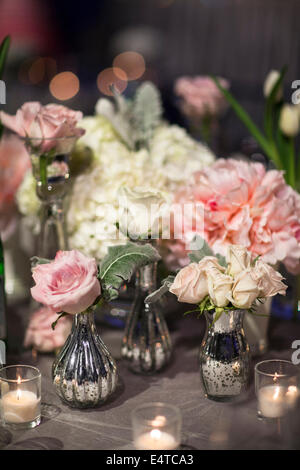 Nahaufnahme von Vasen mit Rosen und Pfingstrosen auf Tisch mit Kerzenschein votive Halter an der Rezeption, Kanada Stockfoto
