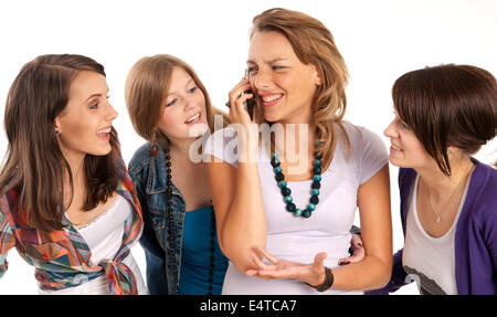 Vier junge Frauen lachen und sahen einander an, eine junge Frau mit Handy geschossen Studio auf weißem Hintergrund Stockfoto