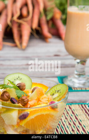 Vitamin-Salat in der Glasschale. Ansicht von oben. Ein Glas Karotten Smoothie von der rechten Seite Stockfoto