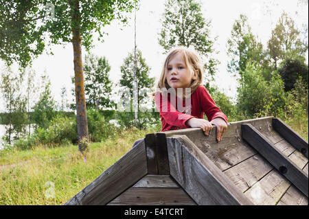 3-jähriges Mädchen im roten Hemd Klettern auf einem hölzernen Schuppen, Schweden Stockfoto