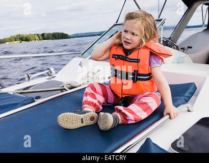 3-jähriges Mädchen in orange Rettungsweste sitting on Top of Motorboot, Schweden Stockfoto