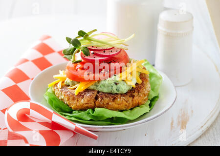 Gluten-freie Kichererbsen-Burger mit Salat, Guacamole, geschreddert Cheddar-Käse, Tomaten, roten Zwiebeln und Sprossen Stockfoto