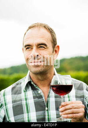 Portrait des Winzers im Weinberg stehen, Glas Wein, Rheinland-Pfalz, Deutschland Stockfoto
