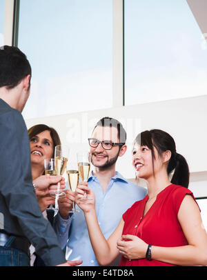 Reife Geschäftsfrau Toasten Gruppe von jungen Geschäftsleuten mit Gläsern Champagner, Deutschland Stockfoto
