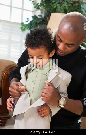 Vater Sohn helfen Knopf Jackett, immer bereit für Kirche Stockfoto