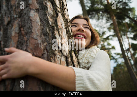 Junge Frau umarmt Tree Trunk, Mannheim, Baden-Württemberg, Deutschland Stockfoto