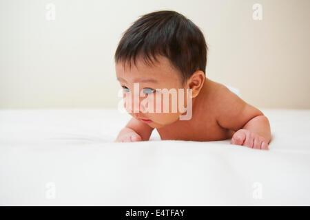 Asiatische Neugeborenes mit Baby-Akne liegt auf Bauch, Studio gedreht auf weißem Hintergrund Stockfoto