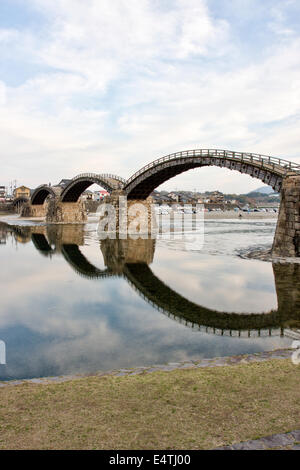 Die historische Holzbogenbrücke Kintai, die den Nishiki River bei Iwakuni am späten Nachmittag überspannt, mit ihrer Spiegelung im Fluss. Stockfoto