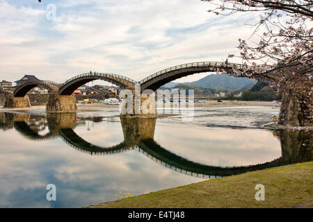 Die historische Holzbogenbrücke Kintai, die den Nishiki River bei Iwakuni am späten Nachmittag überspannt, mit ihrer Spiegelung im Fluss. Stockfoto