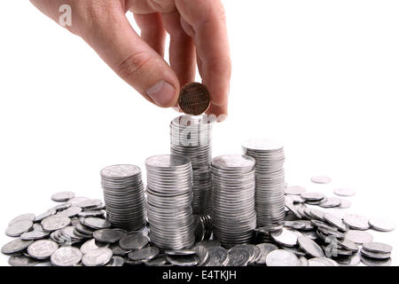 Hand, die Münzen vor weißem Hintergrund hinzufügen Stockfoto