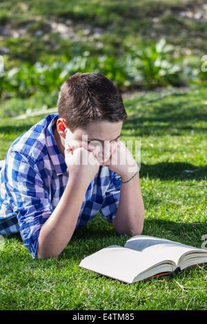 Kleiner Junge liest ein Buch im Wald mit geringer Tiefe Feld und Kopie Stockfoto